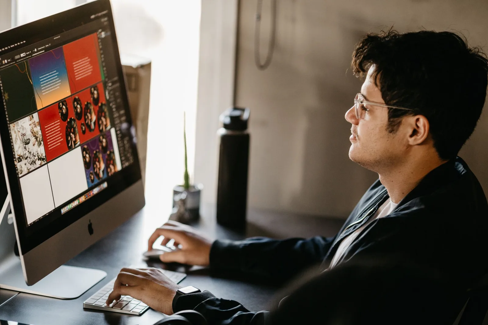 Desktop computer-এ visual website design পরীক্ষা করছেন একজন designer