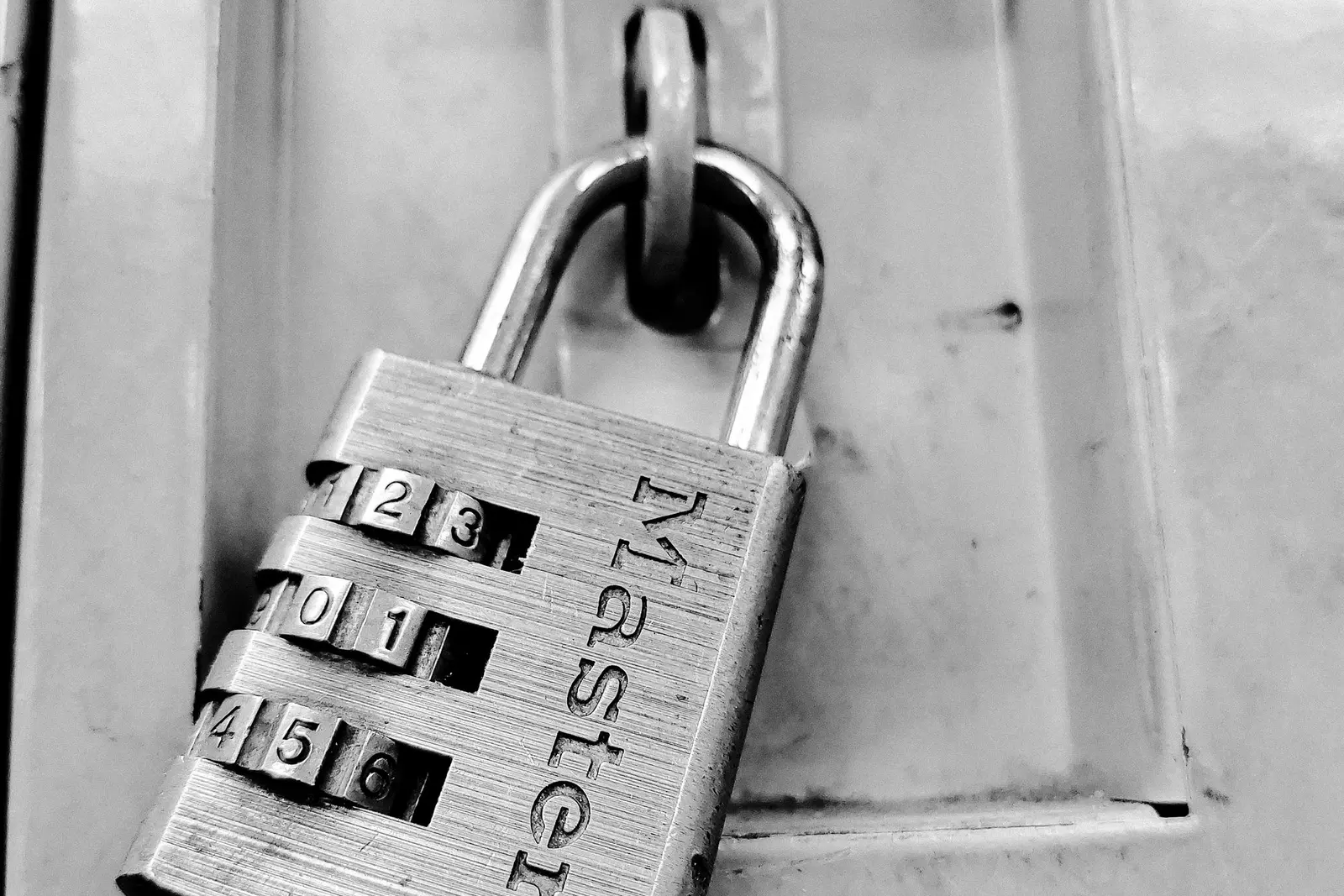 ধাতব locker-এ লাগানো number combination padlock-এর সাদা-কালো close-up