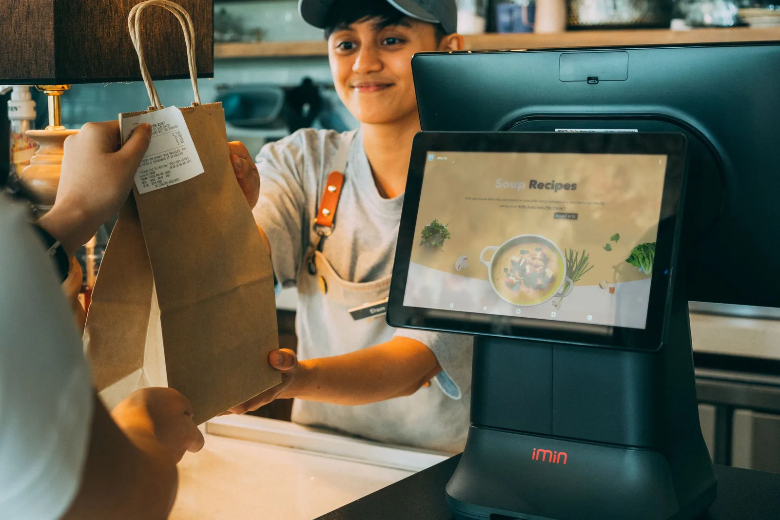 দোকানের counter থেকে receipt-সহ paper bag customer-কে দেওয়া হচ্ছে